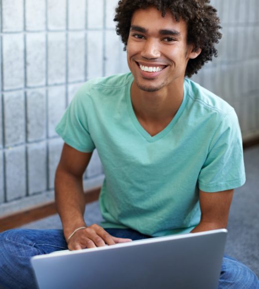 A handsome young ethnic student sitting with his laptop.